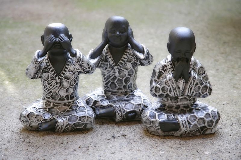 Photograph of three Buddha statues. One is covering its eyes, one is covering its ears, and one is covering its mouth.