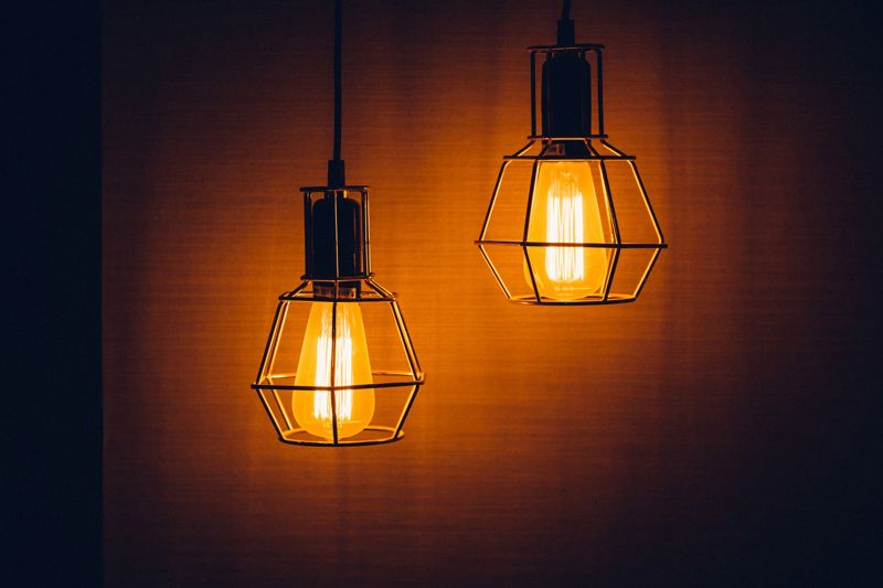 Photograph of two overhead lightbulbs hanging next to a wall.