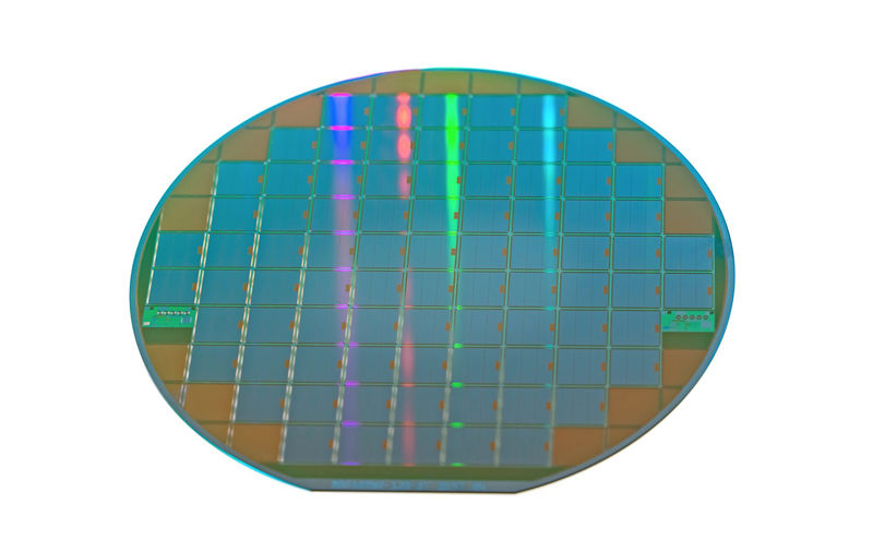 Photograph of a silicon wafer with chips isolated on white background.