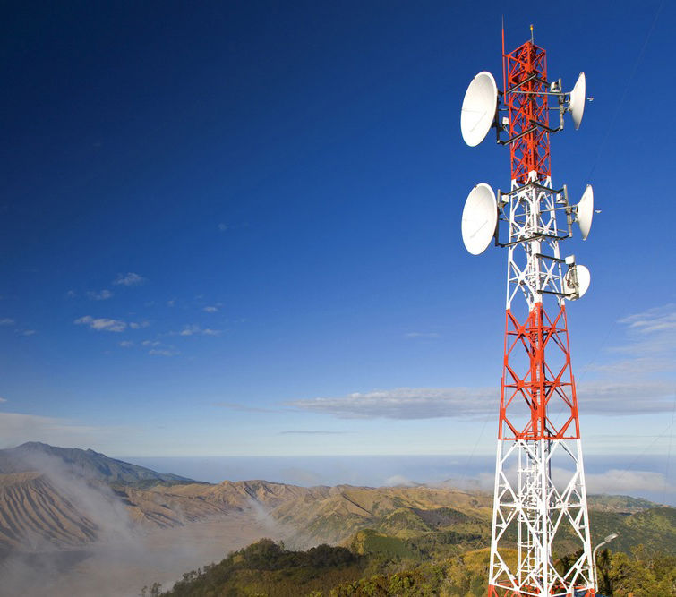 Photograph of a red and white telecommunications antenna with satellite receivers on top of a mountain.