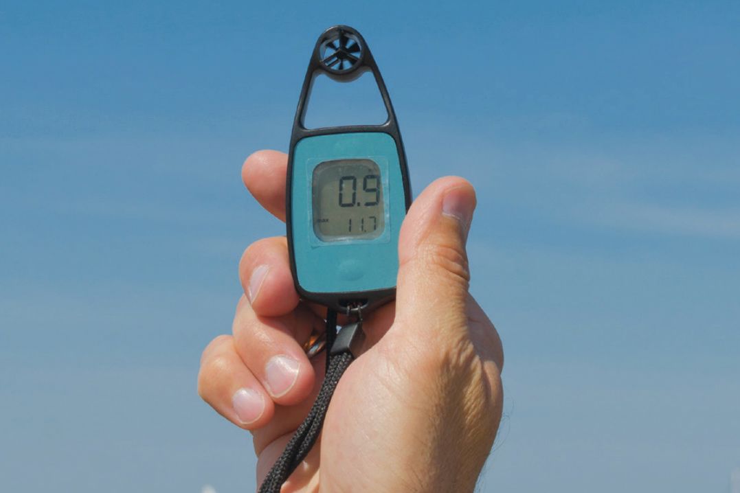 A handheld anemometer device showing a reading of 0.9.