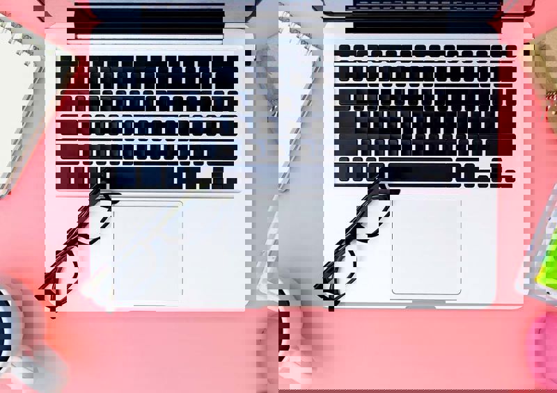 A photograph from a teacher's desk with a laptop, coffee mug, glasses and post-it notes.