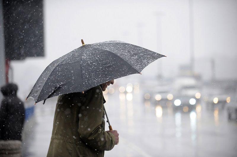 Photograph of a person holding an umbrella on a rainy day.