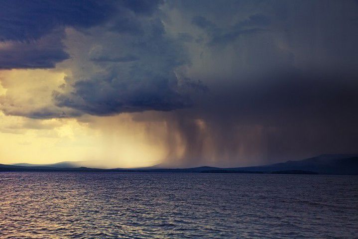 A photograph of rain clouds over a lake.